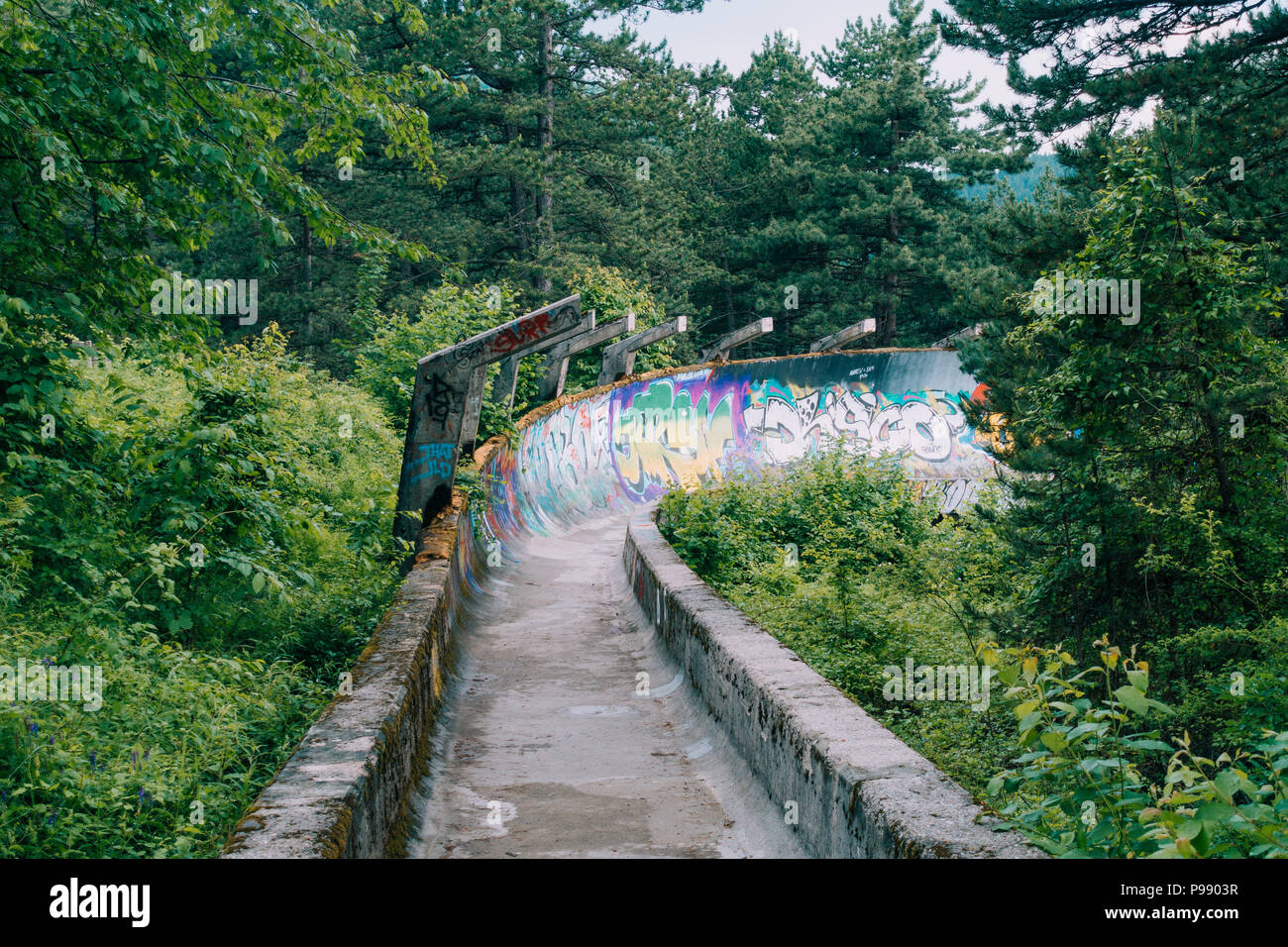 Le désormais ancien béton des Jeux Olympiques de Sarajevo 1984 piste de bobsleigh et de luge à travers la forêt des courbes, couverts de graffitis Banque D'Images