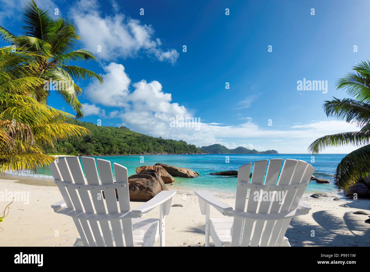 Chaises de plage sur la plage de sable fin avec palmiers et mer turquoise. Banque D'Images
