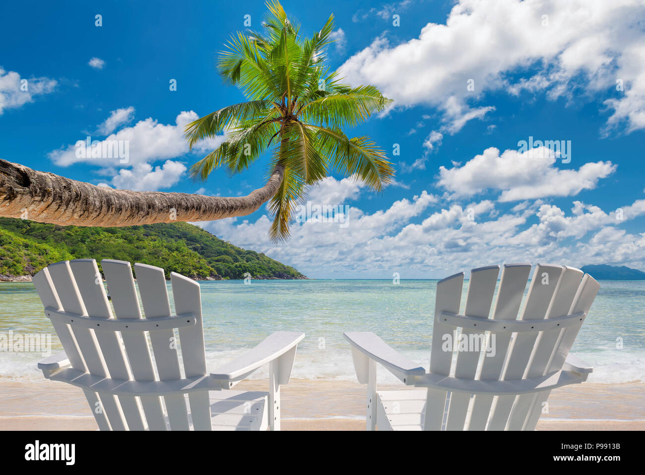 Chaises de plage sur la plage de sable fin avec palmiers et mer turquoise. Banque D'Images