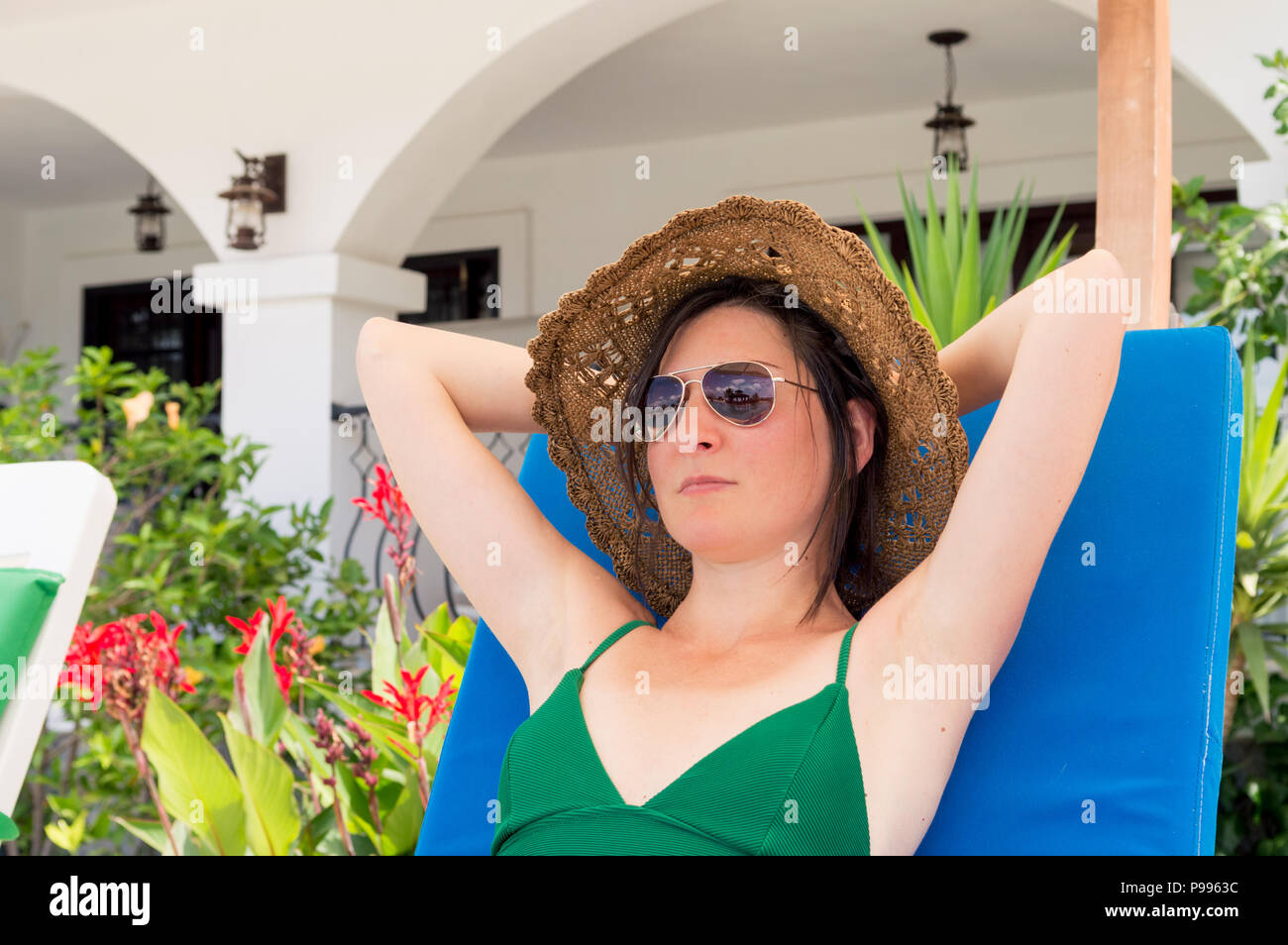 Belle Caucasian woman wearing Sunglasses and hat de vous détendre sur une chaise longue dans un resort hotel Banque D'Images