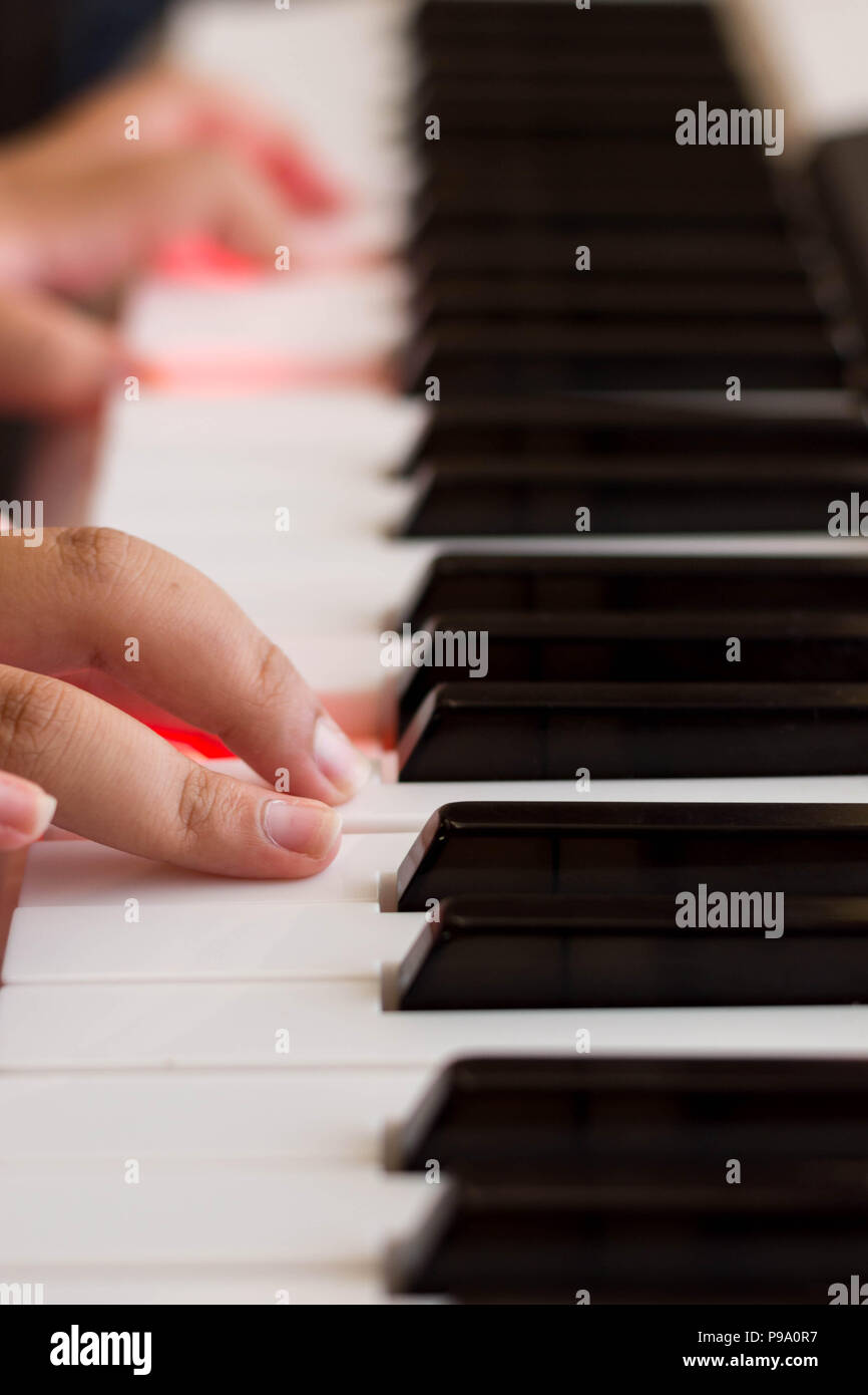 Main sur un clavier de piano avec feux rouges dans les clés Banque D'Images