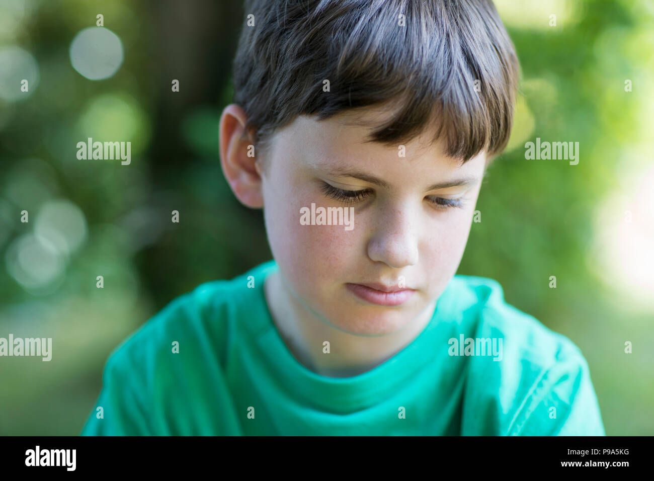 Close Up of malheureux garçon assis à l'extérieur dans jardin Banque D'Images