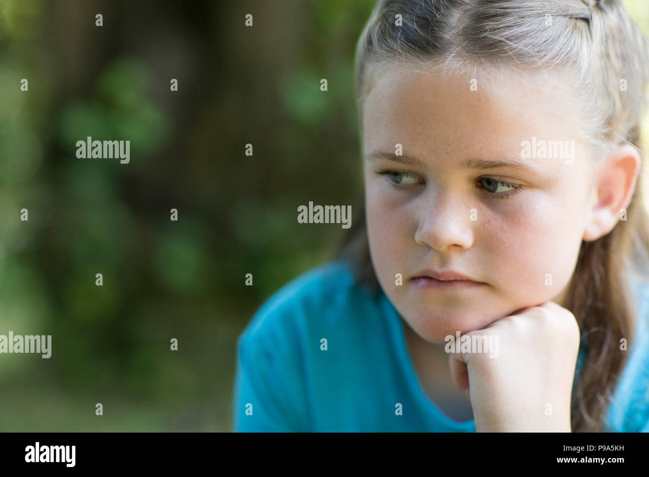 Close Up of malheureux Girl Sitting Outdoors In Garden Banque D'Images