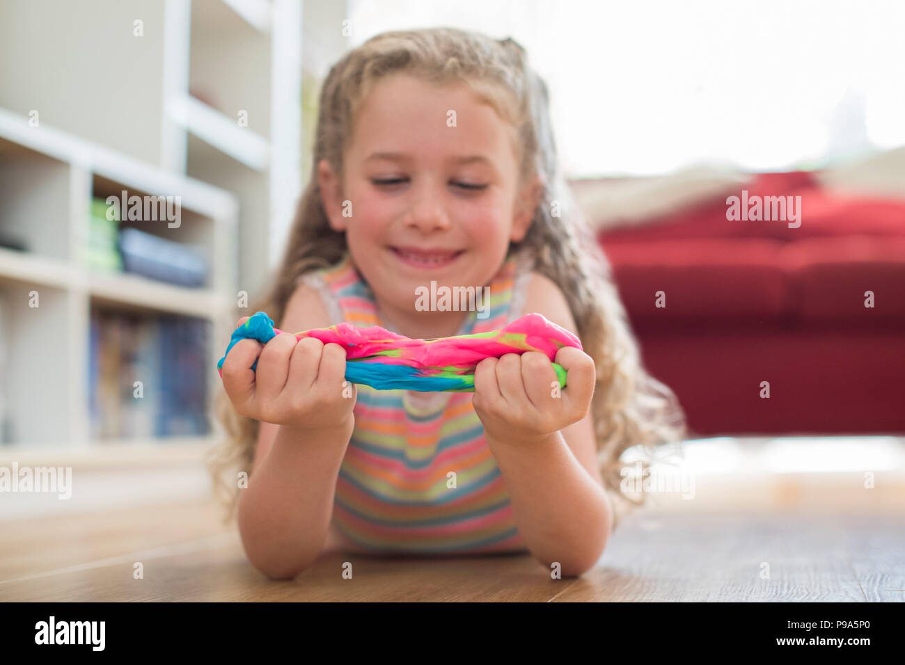 Young Girl Lying On Floor jouant avec Slime colorés Banque D'Images