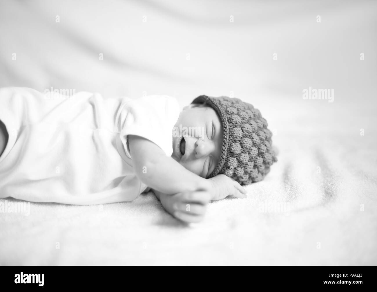 Nouveau-né en étoffes hat allongé sur le drap blanc. Banque D'Images