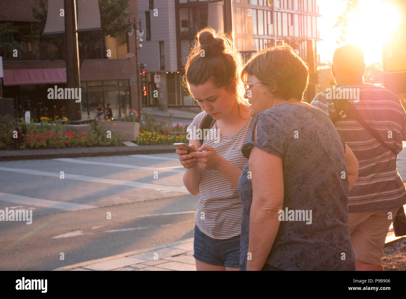 Young Woman phone direction avec mère à côté Banque D'Images