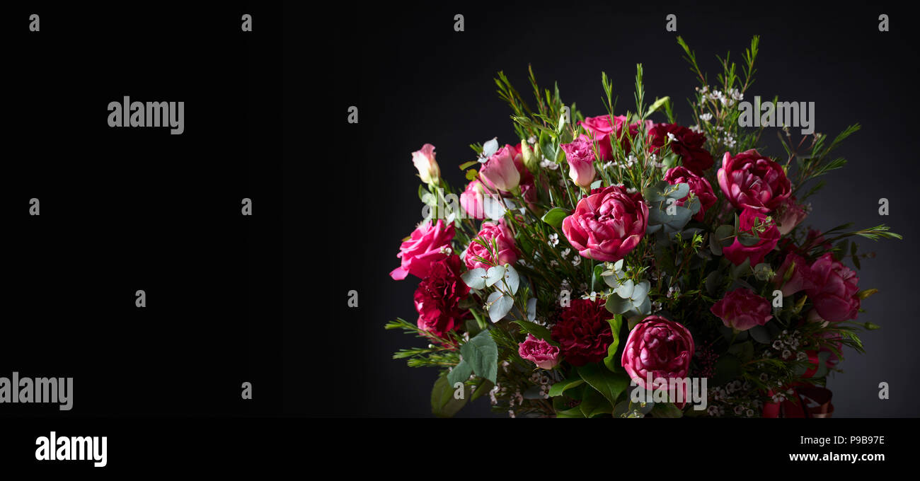 Close up of bouquet coloré avec des roses rouges et pivoines sur fond noir. De belles fleurs sur fond noir avec de l'espace libre pour votre texte. Banque D'Images