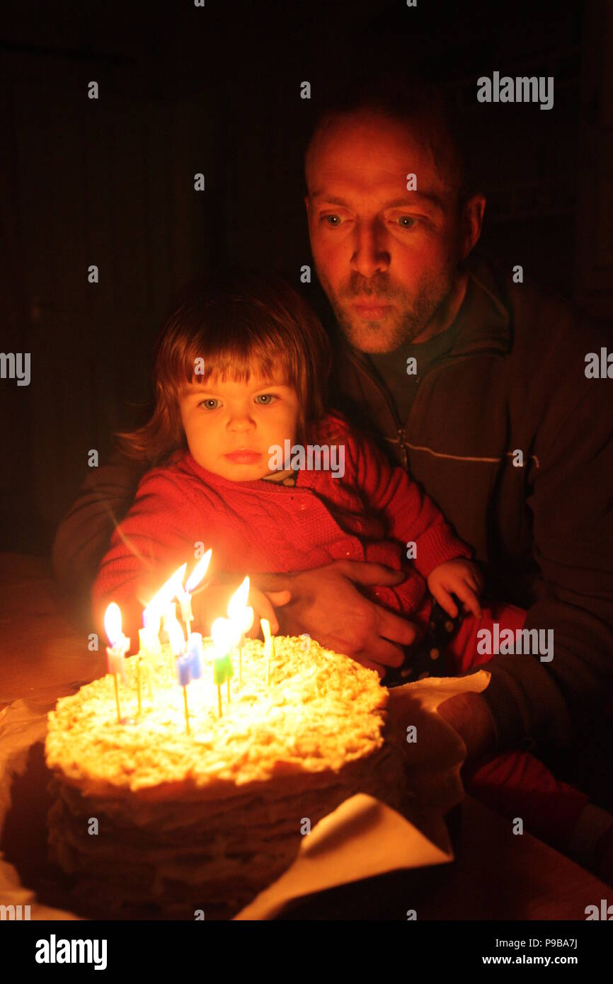 Pere Et De La Jeune Fille Assise Dans La Lumiere Chaude Naturelle Blowing Candles Sur Gateau D Anniversaire Pour Son Deuxieme Anniversaire Fille Photo Stock Alamy