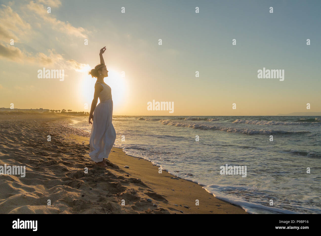 Femme aux bras levés, pieds nus, se sentir heureux, vivant et libre dans la nature en méditant à sandy beach misty propre respiration d'air frais de l'océan au crépuscule. Vacances d'concept de vie Banque D'Images