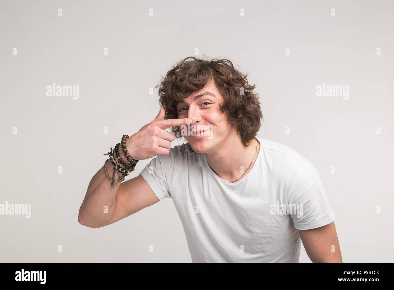 Portrait de jeune homme drôle pointant sur son nez en blanc T-shirt Banque D'Images