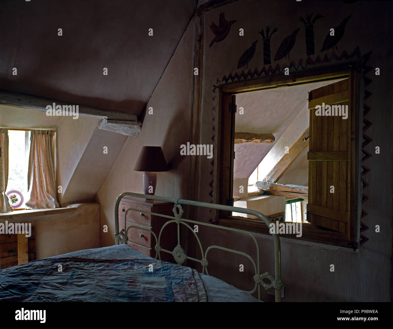 Fenêtre d'intérieur à 90 ans une chambre mansardée avec un lit en laiton peint vintage peint Banque D'Images