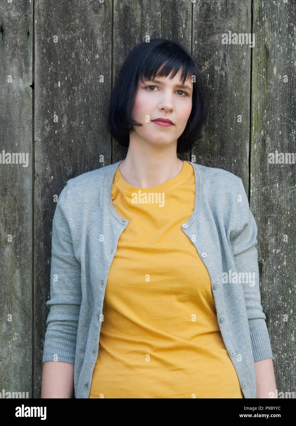 Une femme brunette se penchant contre un vieux mur. Banque D'Images