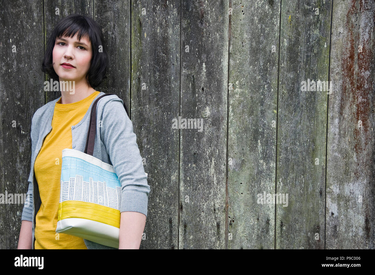 Un portrait d'une femme appuyée contre un mur. Banque D'Images