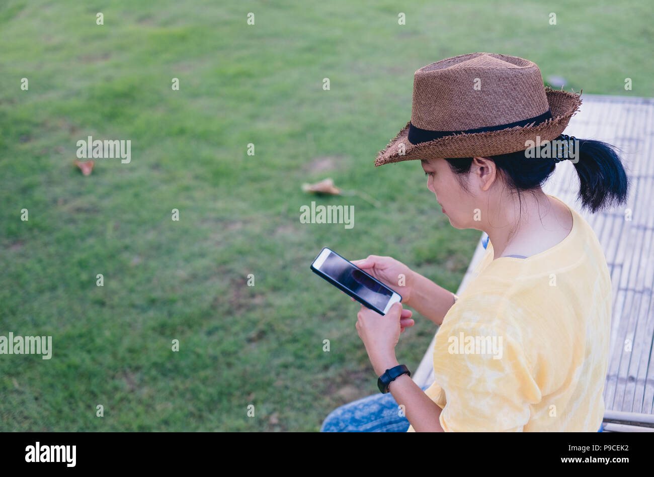 Femme Asiatique porter hat assis à l'extérieur utiliser mobile téléphone au jardin avec sentiment chill out.relax vie Loisirs Banque D'Images