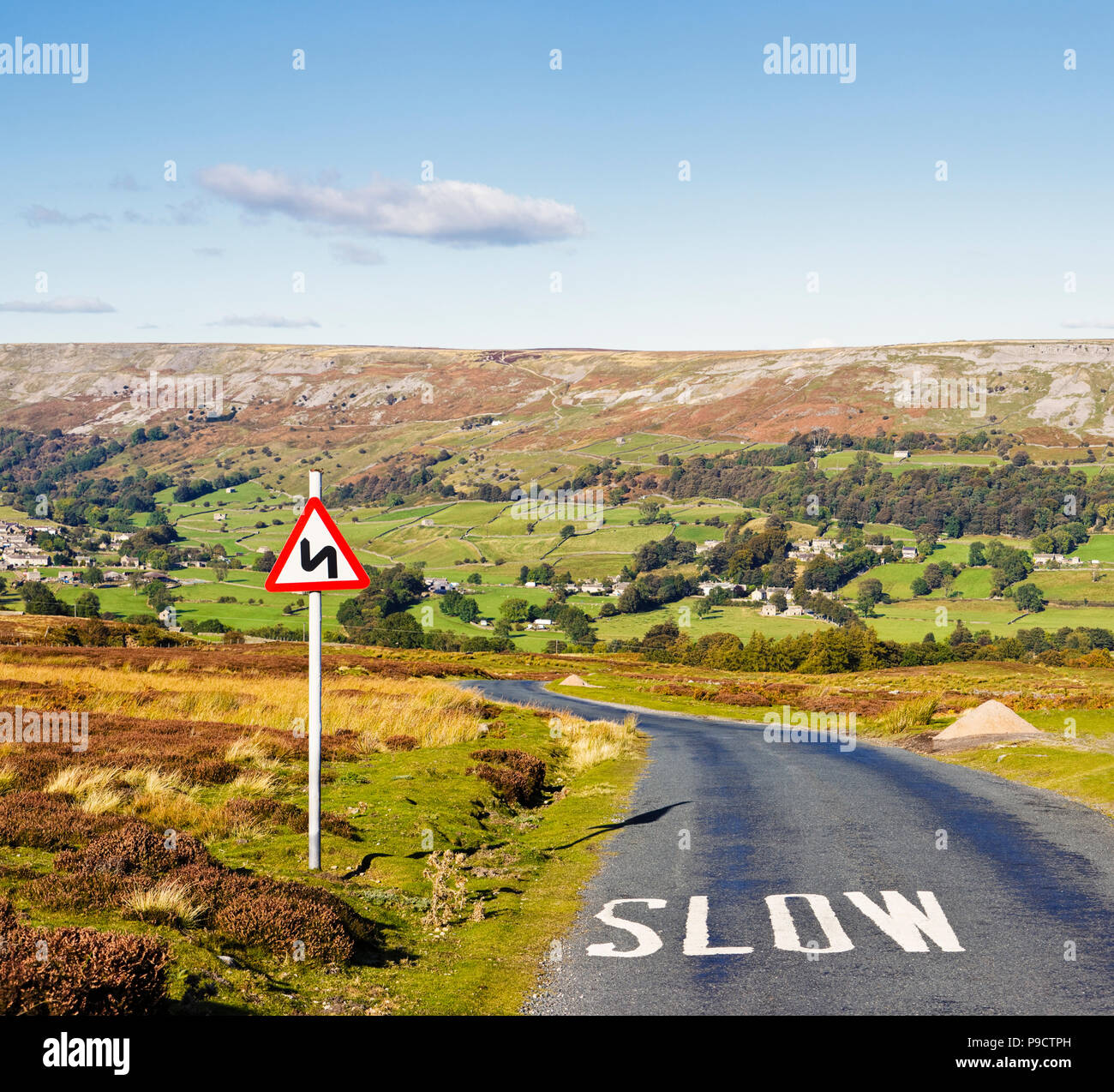 Panneau routier UK, avertissant des virages dangereux à venir et "Ralentir" peint sur la surface de la route, Parc national des Yorkshire Dales, Angleterre Banque D'Images