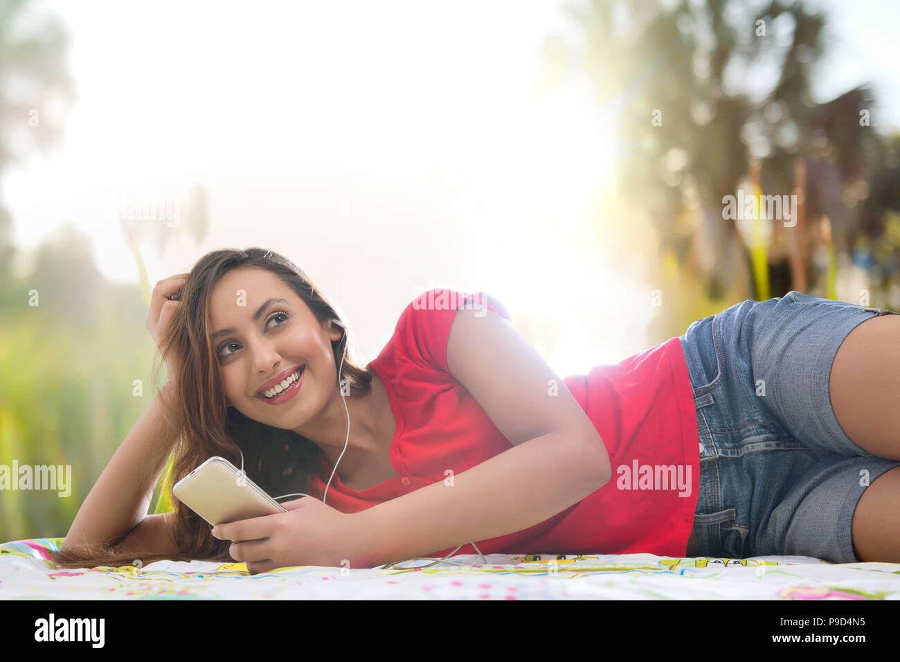 Jeune femme à la recherche de son téléphone cellulaire dans un parc et d'écouter de la musique Banque D'Images