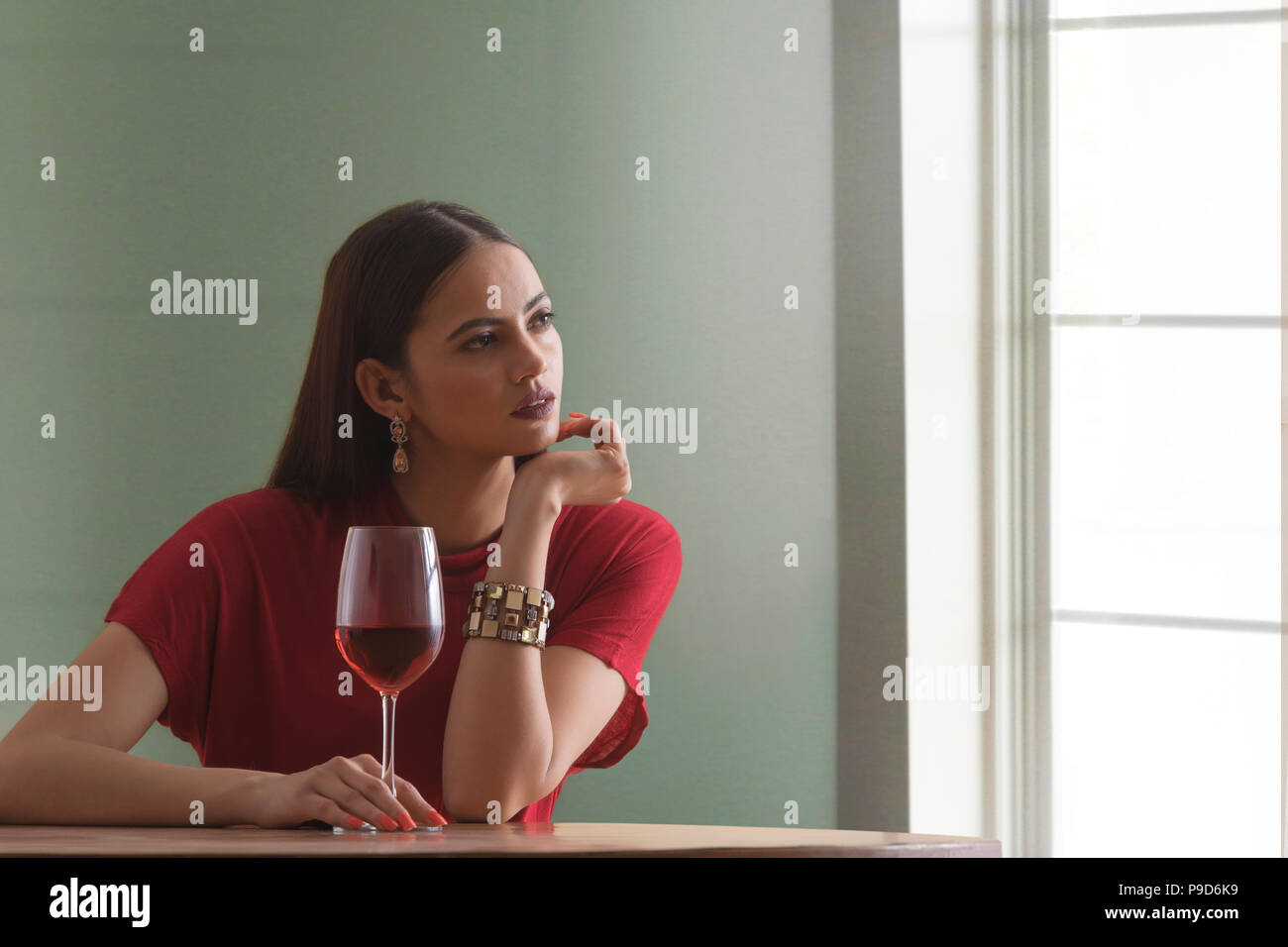 Jeune femme tenant un verre de vin sitting at table Banque D'Images