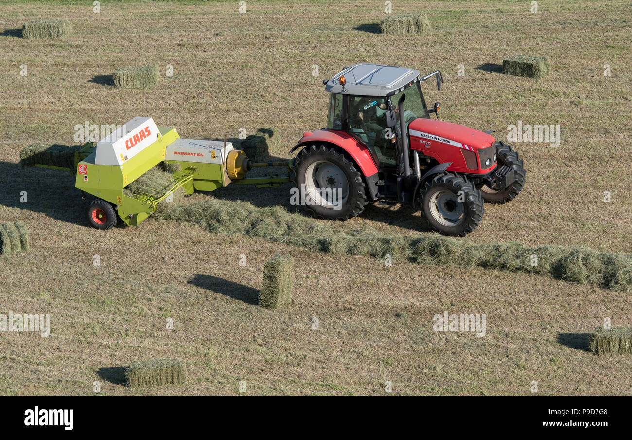 Agriculteur de Swaledale, Yorkshire du Nord La réalisation de balles de foin, à l'aide d'un et un Massey Ferguson 5470 Claas ramasseuse-presse. Banque D'Images