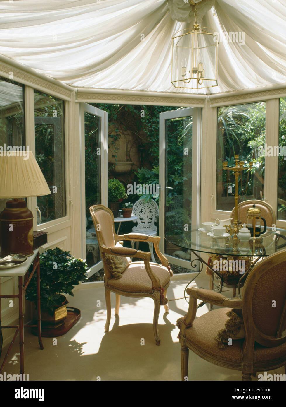 Véranda salle à manger avec plafond crème stores et portes-ouvertes à patio jardin Banque D'Images