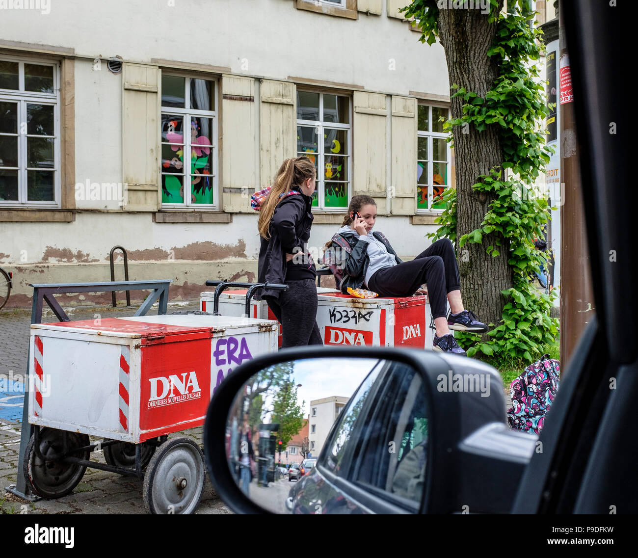 2 adolescentes chat, téléphone, assis sur des chariots de livraison de journaux, Strasbourg, Alsace, France, Europe, Banque D'Images