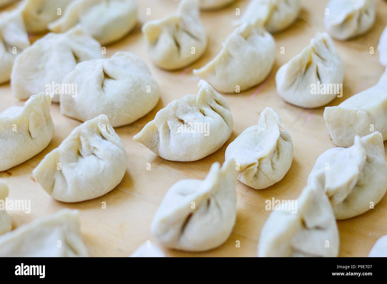 Close-up of Chinese Dumplings crus placé sur planche de bois. S'appelle dumplings jiaozi en chinois, est une populaire de la cuisine chinoise traditionnelle. Banque D'Images