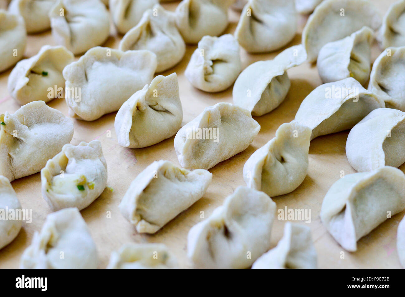 Boulettes crues chinois placé sur planche de bois. Les boulettes, appelés jiaozi en chinois, populaire pour le festival du Nouvel An chinois. Banque D'Images