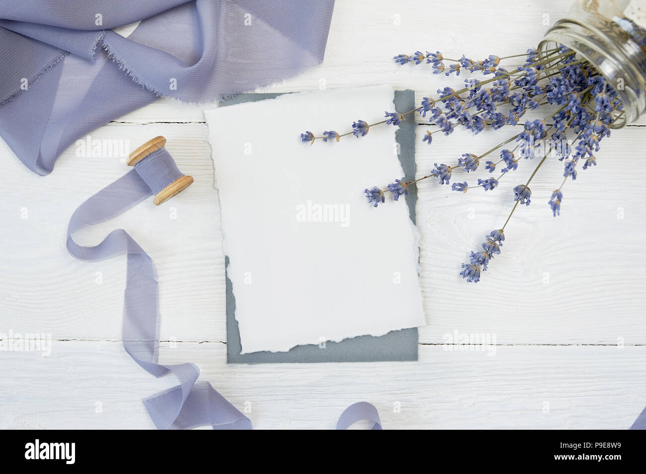 Carte vierge blanc sur fond de fleurs de lavande avec du ruban bleu sur fond blanc. Immersive avec enveloppe et carte vierge. Mise à plat. Vue d'en haut Banque D'Images