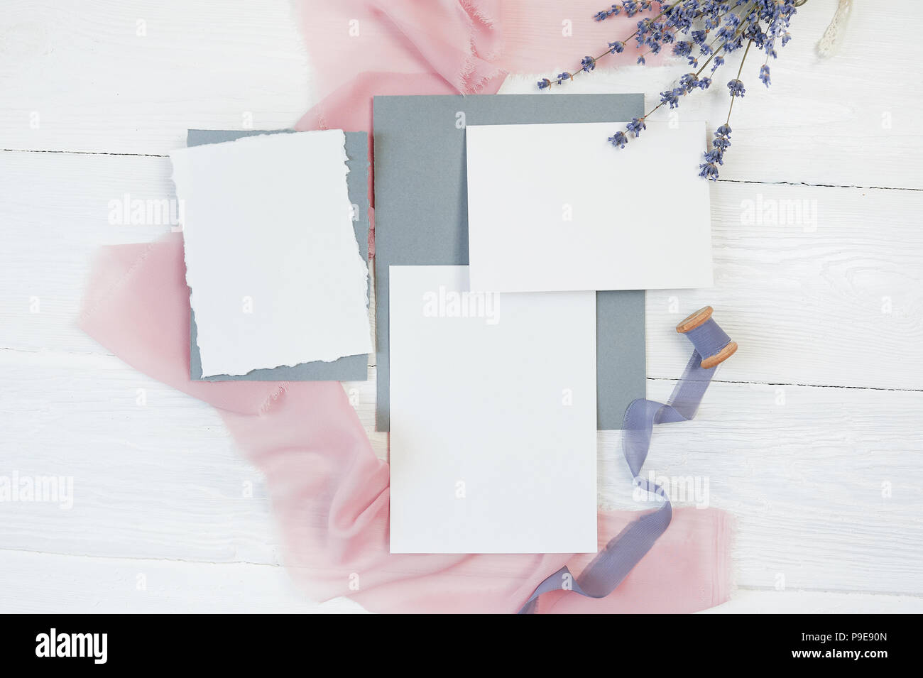 Carte vierge blanc ruban sur un fond de tissu rose et bleu avec des fleurs de lavande sur un fond blanc. Immersive avec enveloppe et carte vierge. Mise à plat. Vue d'en haut Banque D'Images