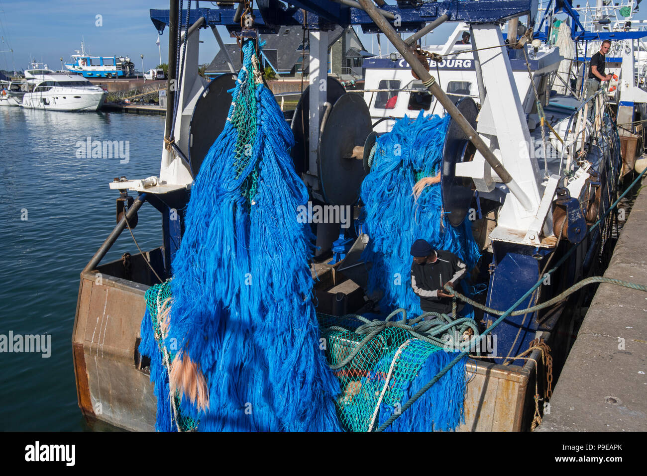 Pêcheur noir travaillant sur bateau de pêche chalutier amarré dans le port de Saint-Vaast-la-Hougue, Manche, Normandie, France Banque D'Images