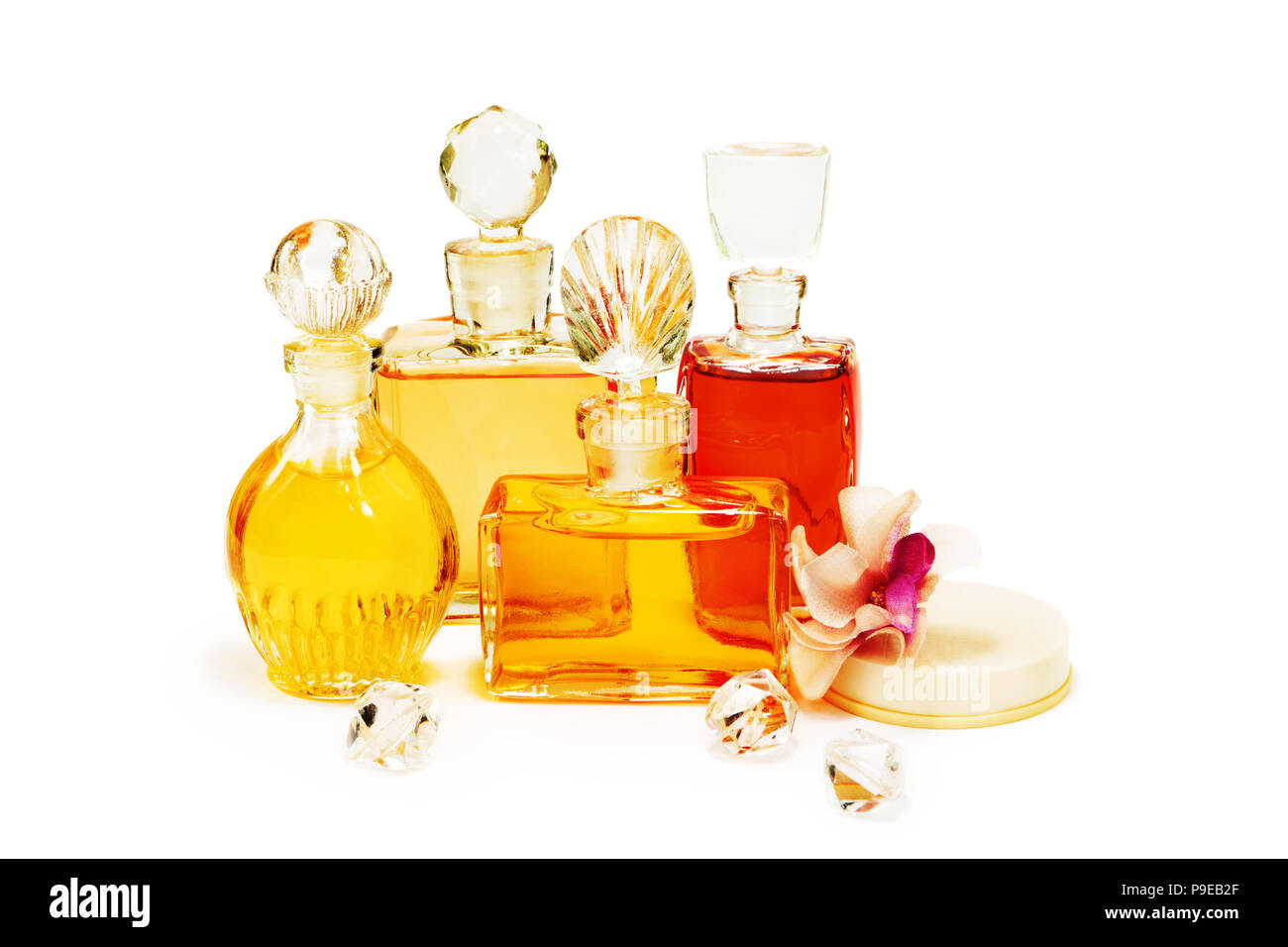 Le groupe des Flacons à parfum vintage avec les bouchons en verre, d'un cosmétique en poudre dans la boîte en plastique blanc et fleurs artificielles isolated on white Banque D'Images