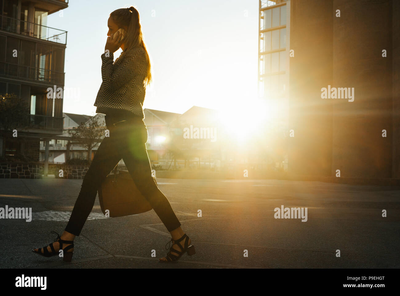 Businesswoman se rendre au bureau tôt le matin de conversations au téléphone mobile. Sac à main femme marche sur la rue de la ville d'office. Banque D'Images