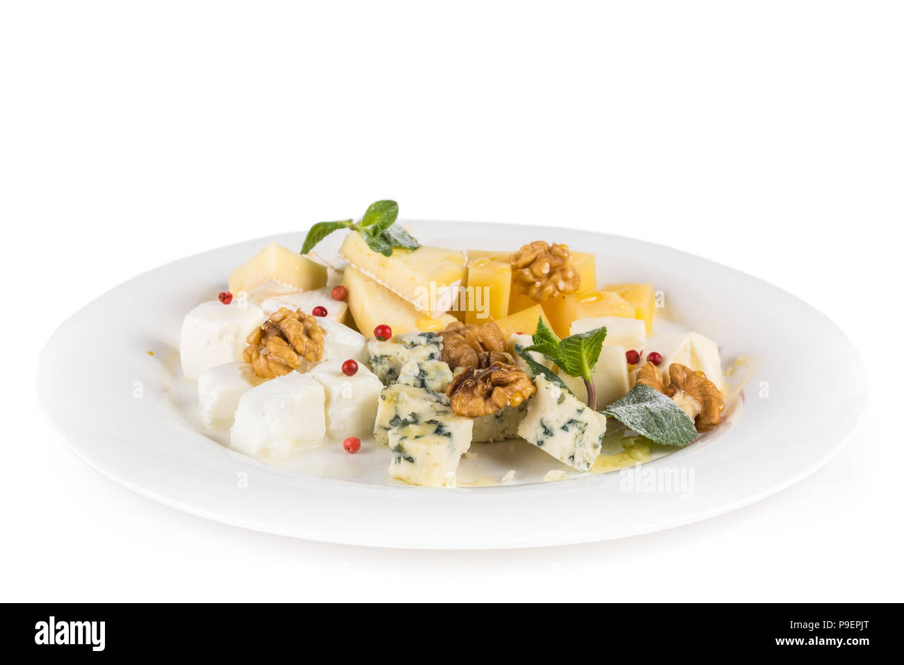 Assiette de fromage : Parmesan, cheddar, gouda, mozzarella et d'autres avec les noix, les canneberges et de menthe sur une assiette. De savoureux hors-d'œuvre. Isolées. Banque D'Images