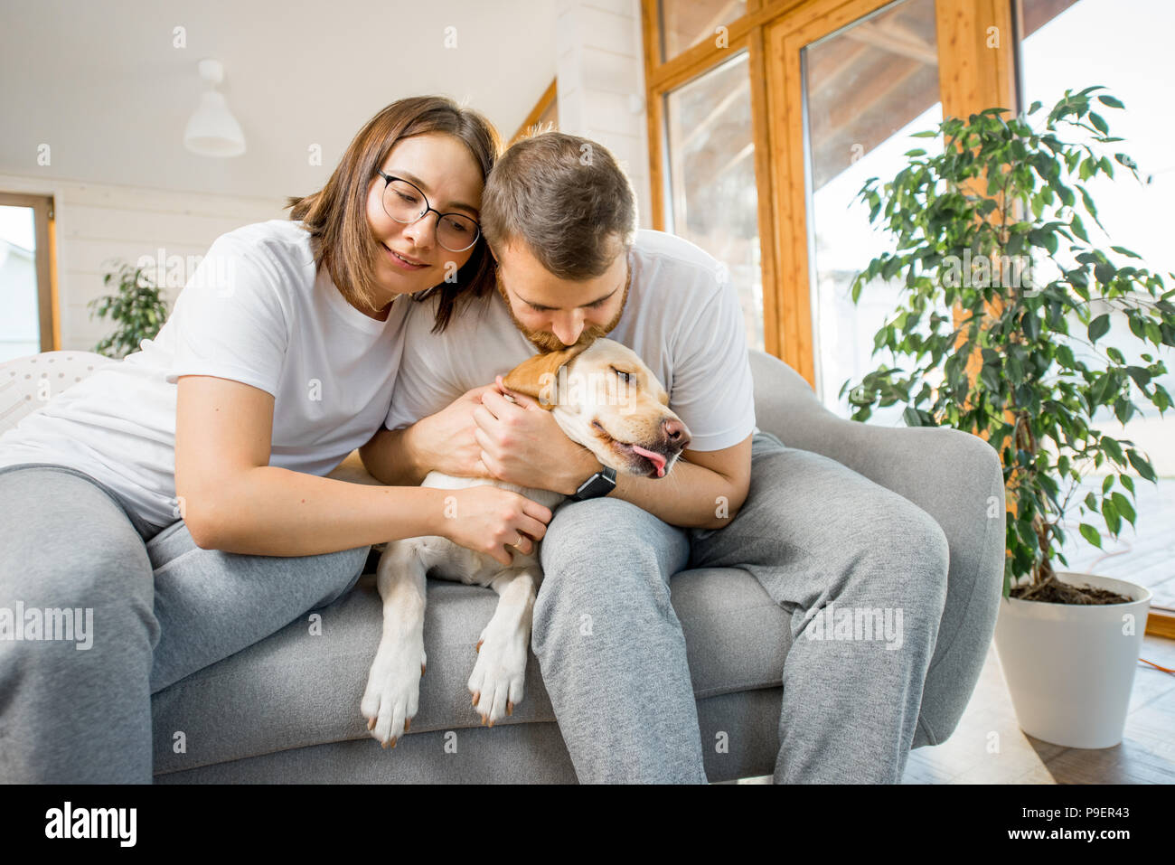 Couple avec chien sur le canapé à la maison Banque D'Images