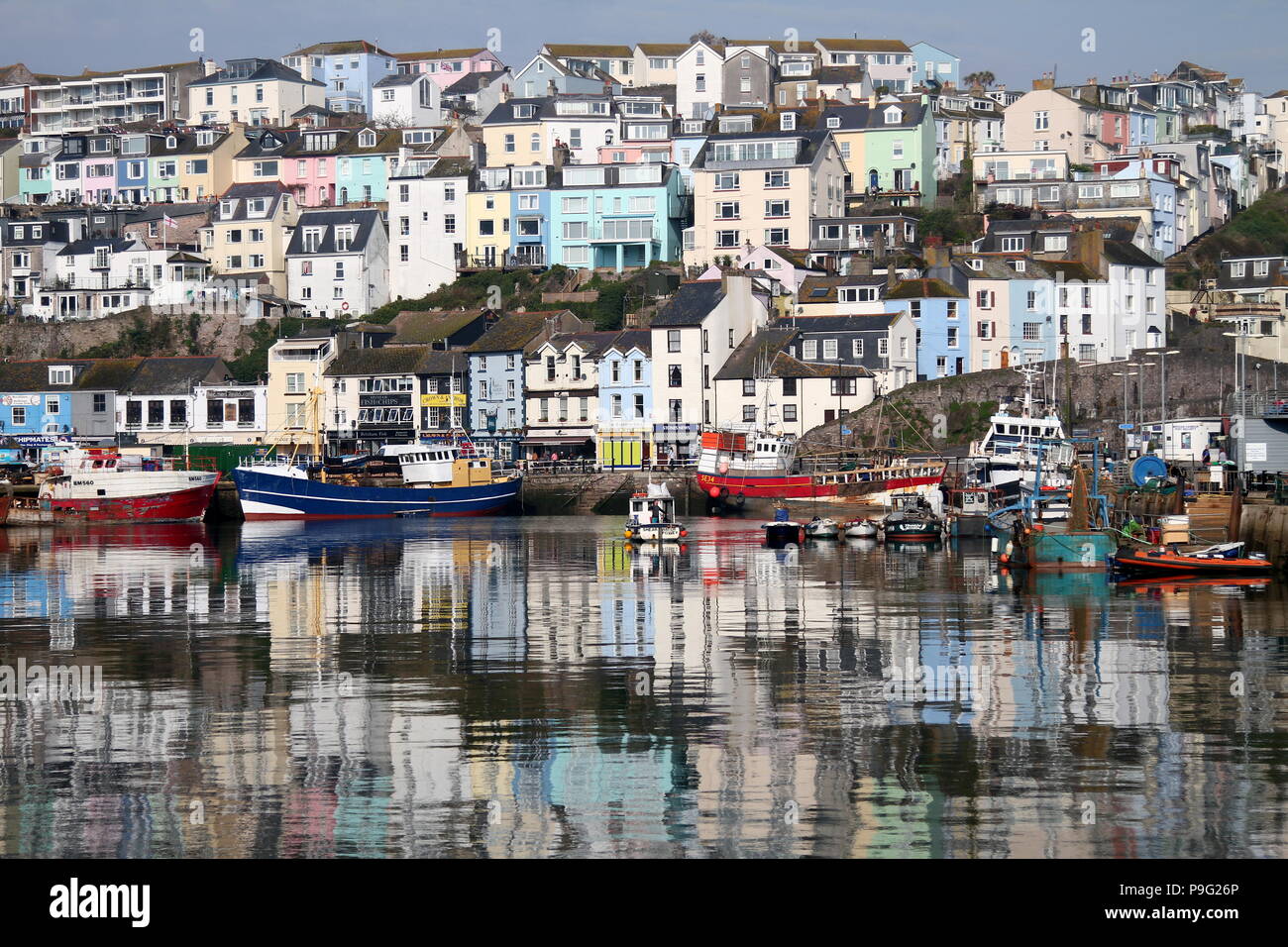 Port de Brixham, Devon, Angleterre : les tons pastel maisons qui se reflètent dans les eaux du port sur un matin ensoleillé Banque D'Images