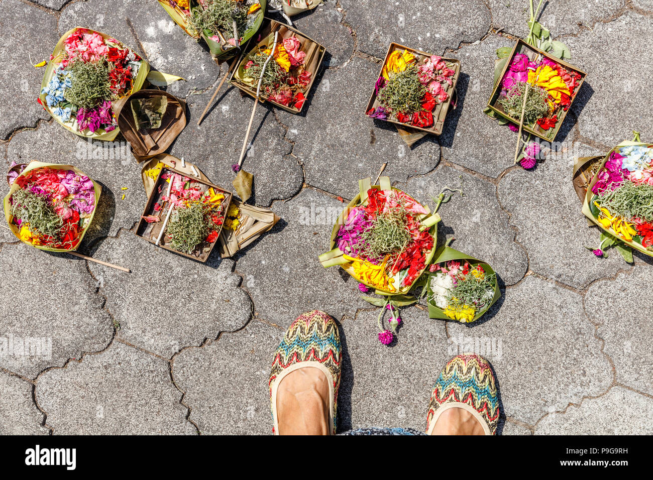 Canang Sari, hindou balinais offrant sur le sol près de ses pieds. Bali, Indonésie. Banque D'Images