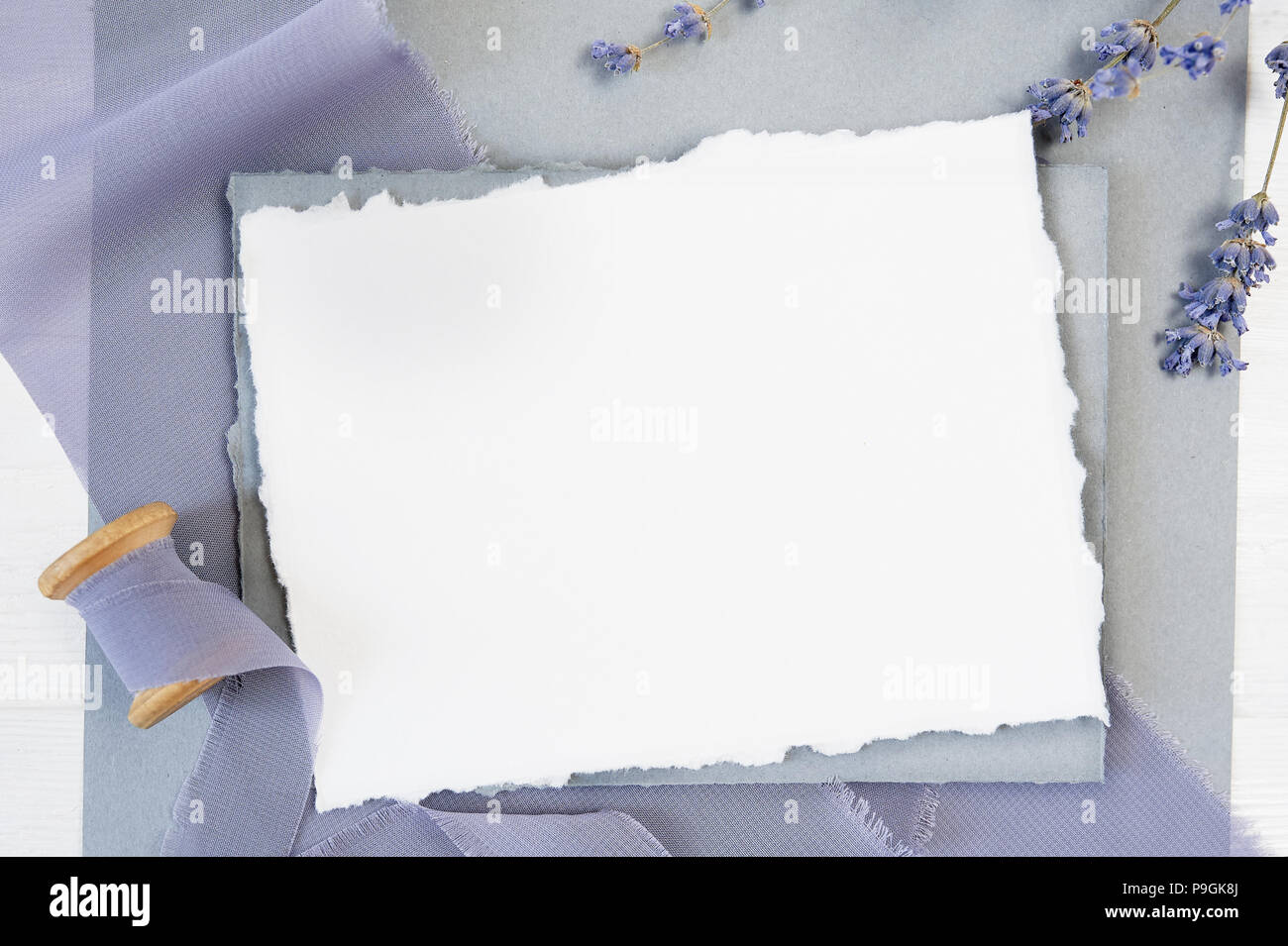 Carte de voeux vierge blanc ruban sur un fond de toile bleue avec des fleurs de lavande sur un fond blanc. Immersive avec enveloppe et carte vierge. Mise à plat. Vue d'en haut Banque D'Images