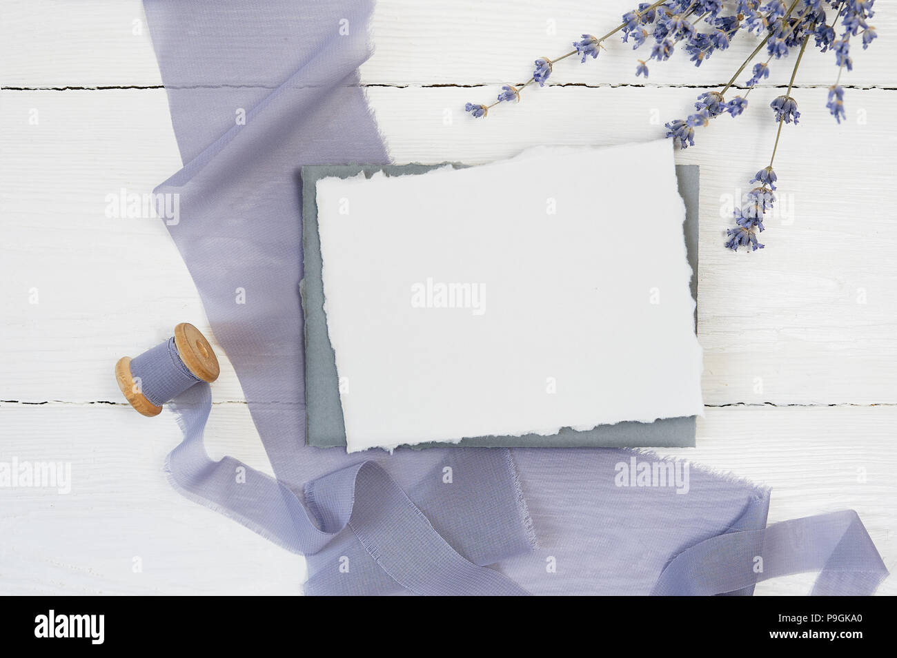 Carte de voeux vierge blanc ruban sur un fond de toile bleue avec des fleurs de lavande sur un fond blanc. Immersive avec enveloppe et carte vierge. Mise à plat. Vue d'en haut Banque D'Images