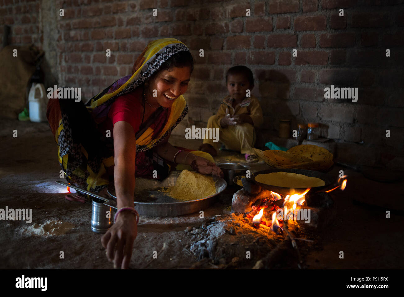 Une femme cuisiner chapattis sur un feu ouvert, dans leur cuisine dans les régions rurales de l'Inde. Banque D'Images