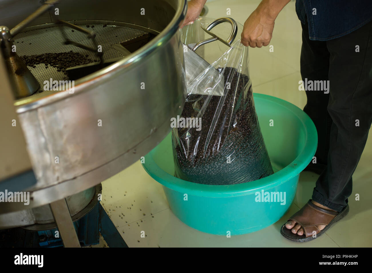 Verser les grains de café torréfiés dans le sac en plastique de la machine torréfacteur pour vendre Banque D'Images