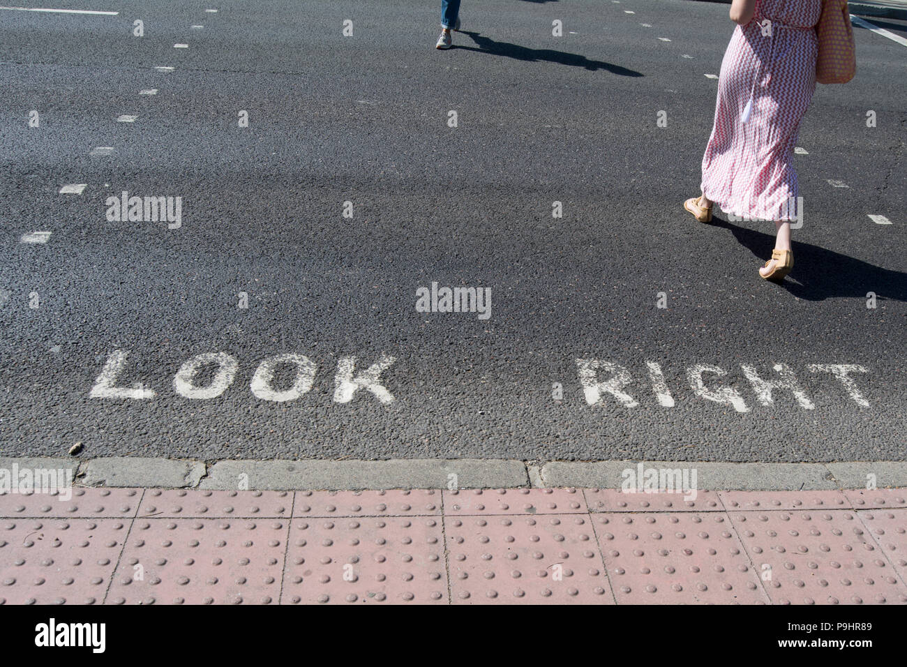 Regardez à droite la signalisation horizontale avec deux personnes de traverser la route dans des directions opposées, à Richmond, Surrey, Angleterre Banque D'Images