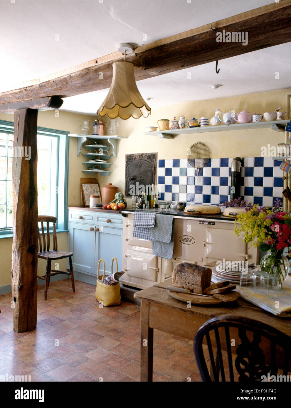 Carrelage blanc +bleu au-dessus d'une Aga crème dans un pays cuisine avec plancher en vinyle et des poutres en bois rustiques Banque D'Images
