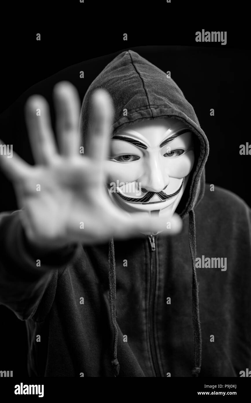 Hacker anonyme portant un masque de Guy Fawkes et une capuche noire Banque D'Images
