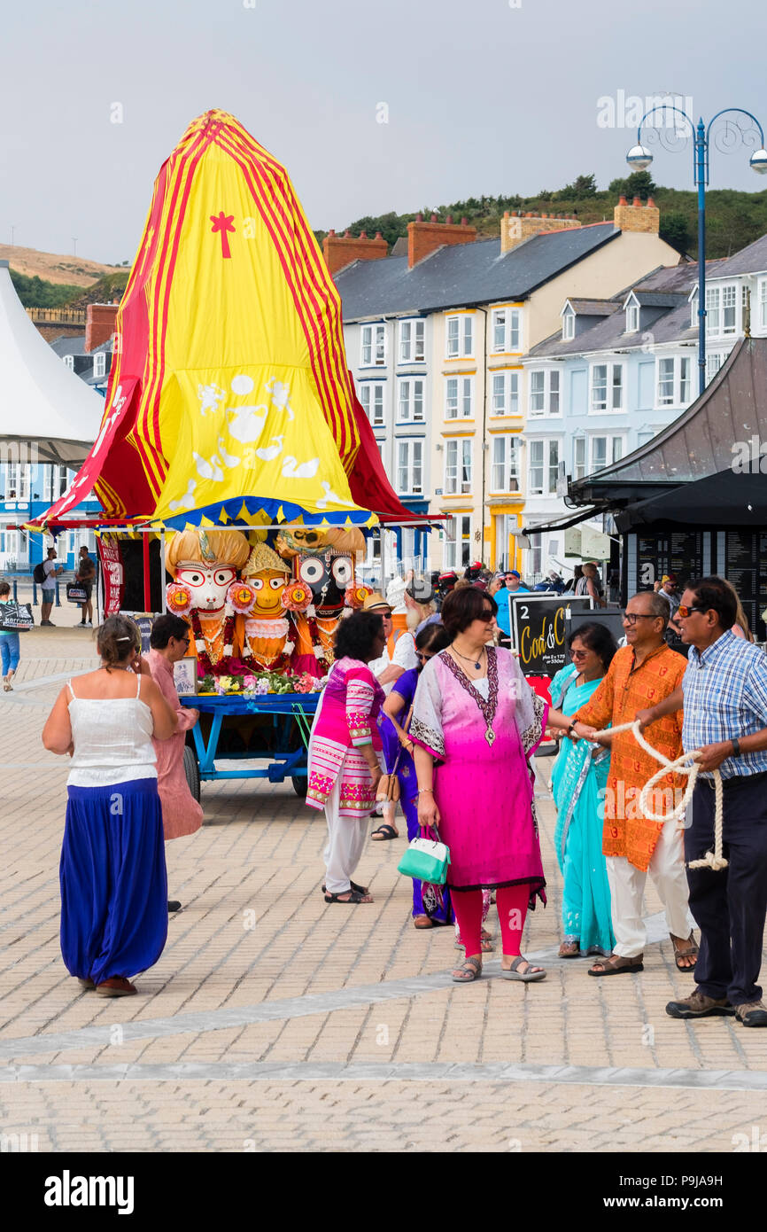 La foi et la religion sur le Royaume-uni : un groupe de dévots Hare Krishna avec leur "Ratha' un temple mobile votive char pour la déité Seigneur Jagannath, chantant comme ils le remorquer le long de la promenade à Aberystwyth, Pays de Galles, Royaume-Uni par un après-midi d'été Banque D'Images