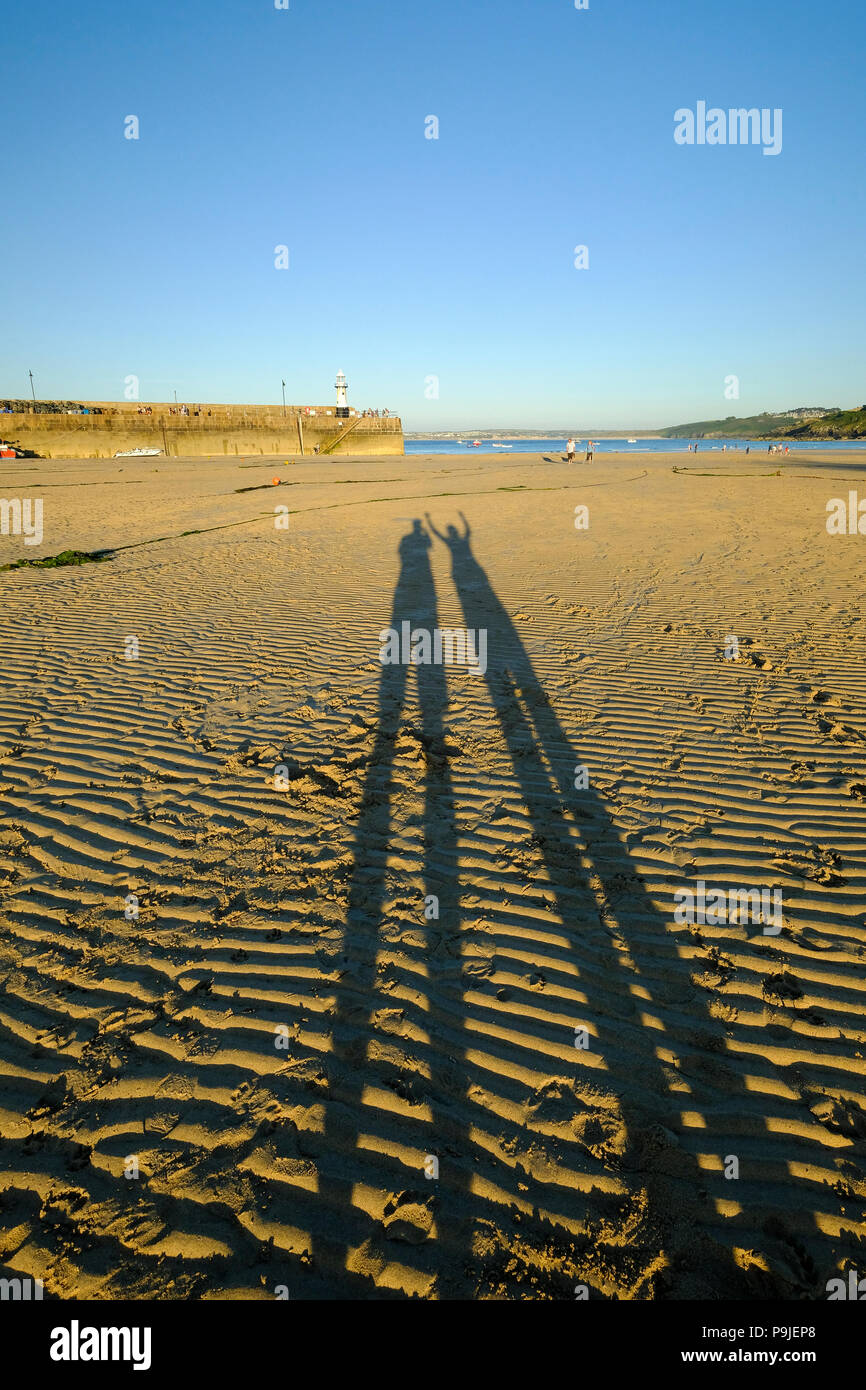 De longues ombres de deux personnes sur la plage dans le soleil du soir à St Ives en Cornouailles Banque D'Images