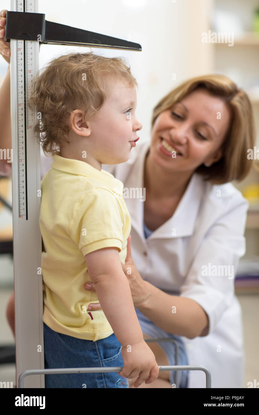 La croissance de l'enfant souriant mesures médecin boy in medical office, profile Banque D'Images