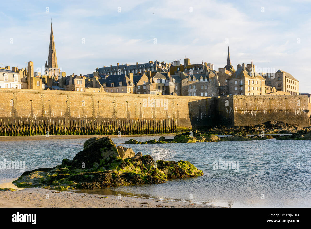 La ville fortifiée de Saint-Malo, en France, au coucher du soleil avec le clocher de la cathédrale dépassant les bâtiments derrière le mur et le fort a la re Banque D'Images La ville fortifiée de Saint-Malo, en France, au coucher du soleil avec le clocher de la cathédrale dépassant les bâtiments derrière le mur et le fort a la re Banque D'Images