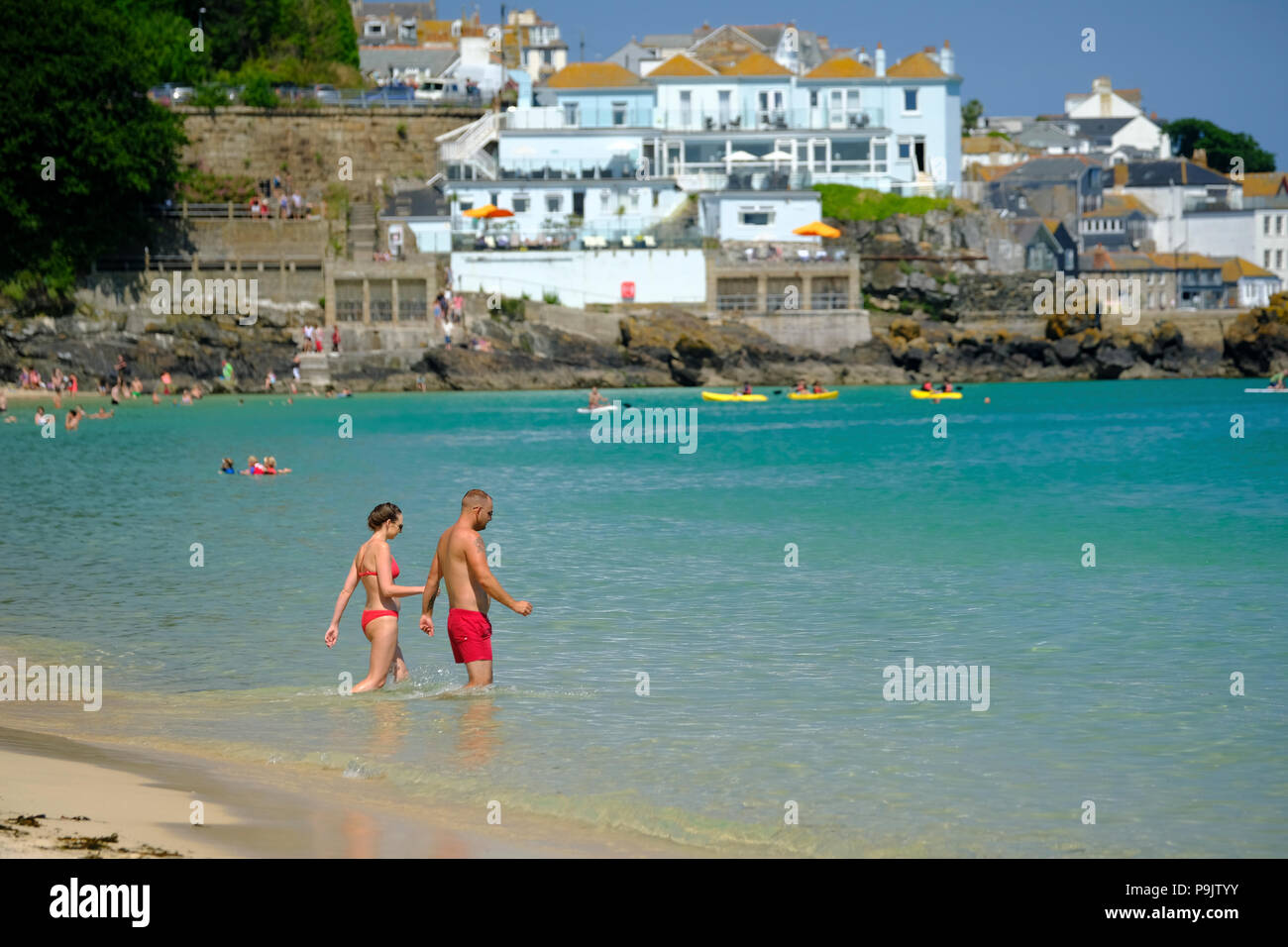 Un jeune couple en train de marcher dans la mer ensemble sur la plage de Porthminster à St Ives Cornwall Banque D'Images