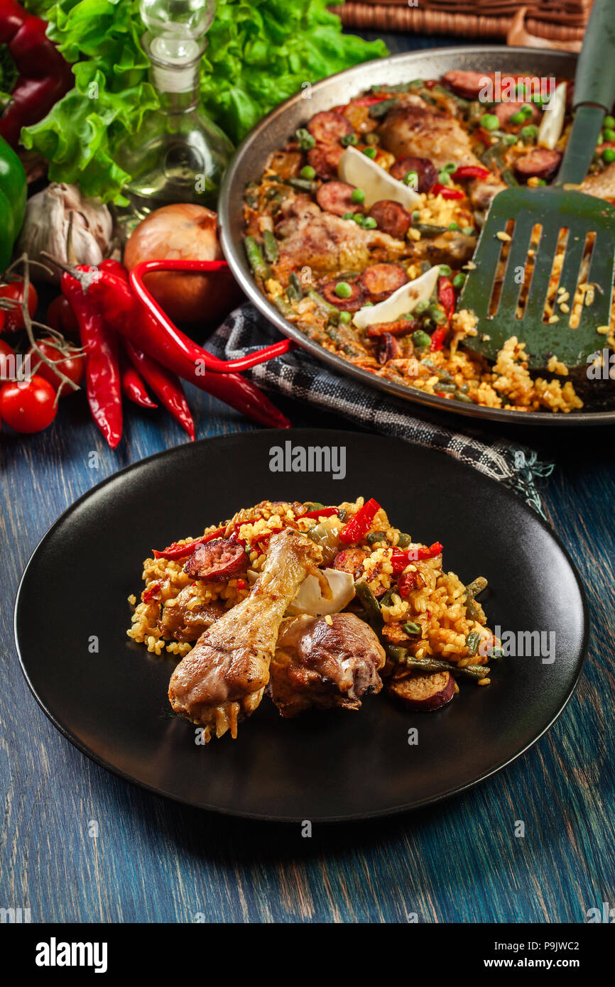 La paella traditionnelle avec des cuisses de poulet, saucisses chorizo et légumes servi sur la plaque noire. Cuisine espagnole. Vue d'en haut Banque D'Images