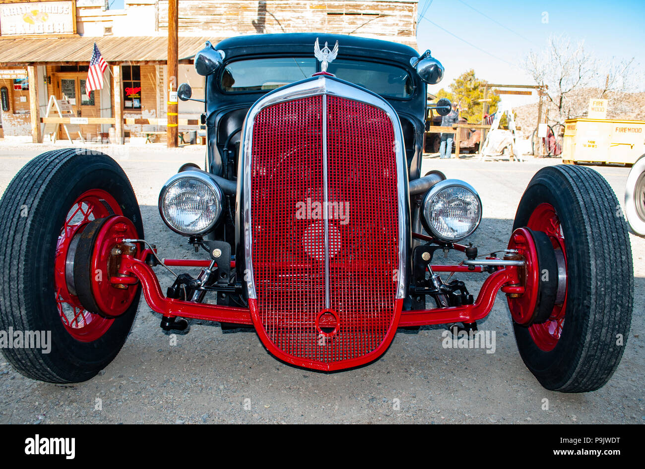 Hot Rod en rouge et noir dans une vieille ville fantôme avec grand mur blanc et un fil rouge personnalisé grill Banque D'Images