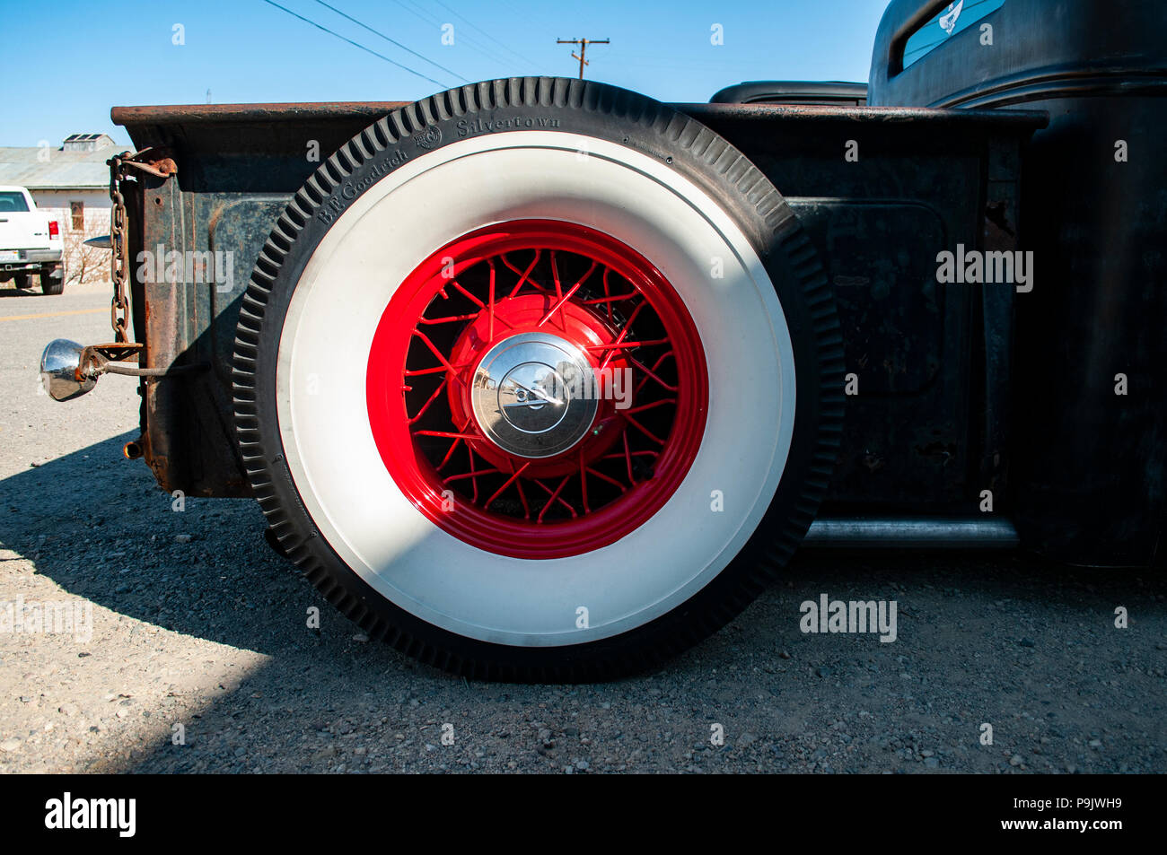 Hot Rod en rouge et noir dans une vieille ville fantôme avec de gros pneus mur blanc Banque D'Images